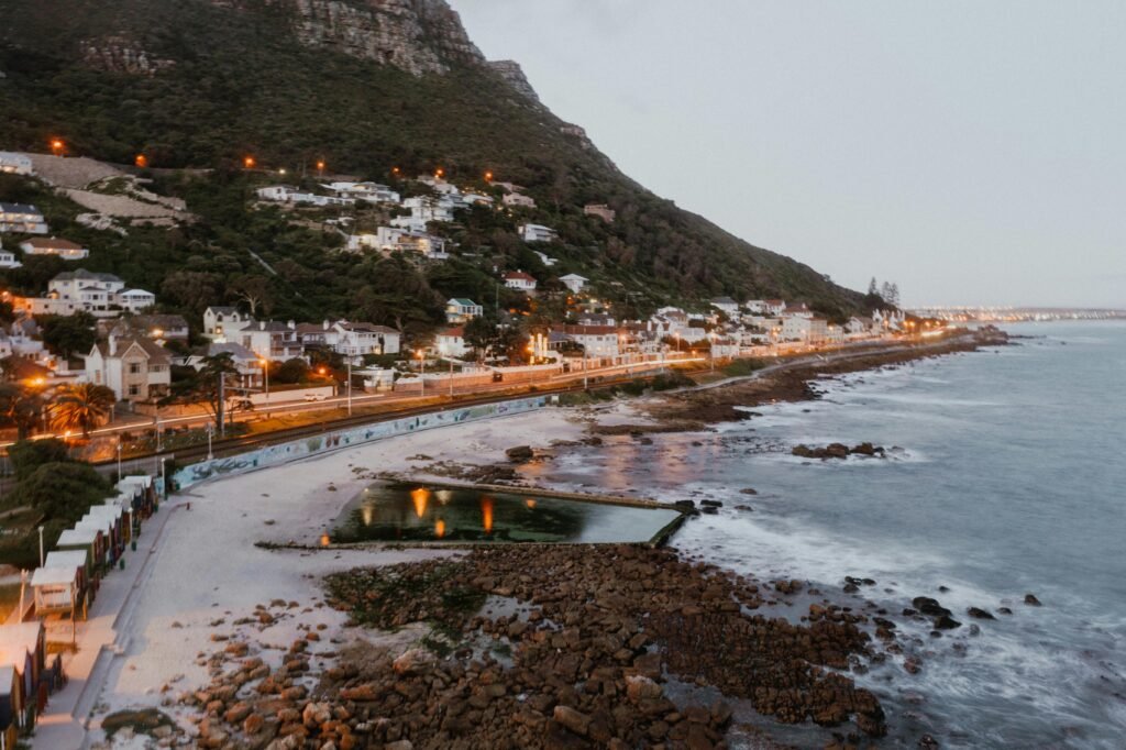 Explore a serene coastal town with mountain backdrop at twilight, capturing urban and natural harmony.